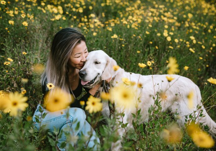 Young Woman Hugs Her Dog In Flower Filled Field